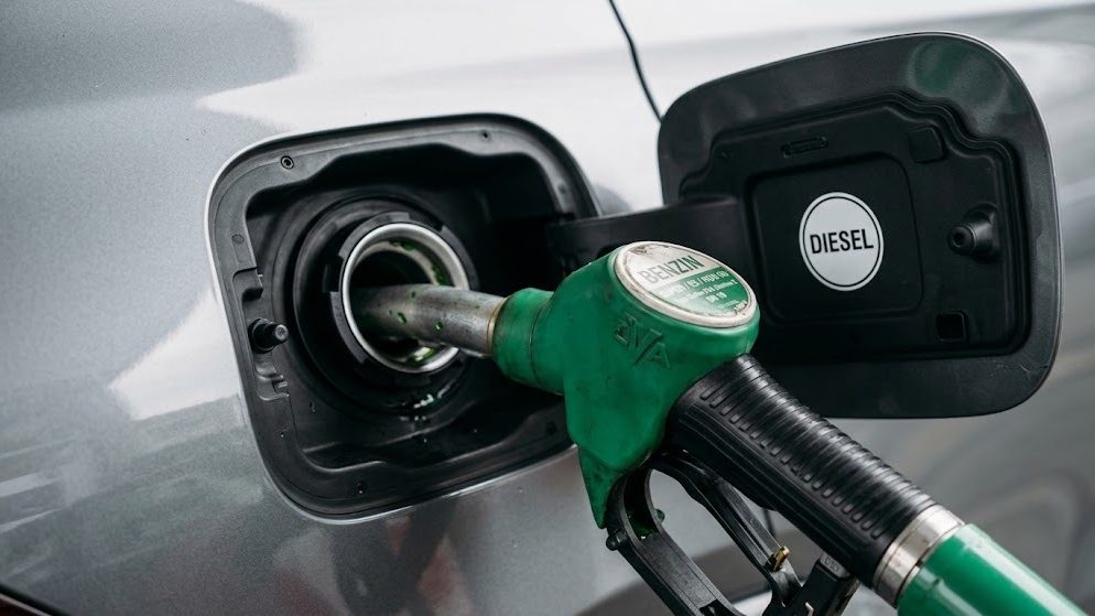 Grüne Benzin-Zapfpistole steckt im Einfüllstutzen eines Fahrzeugs, dessen Tankklappe Diesel ausweist